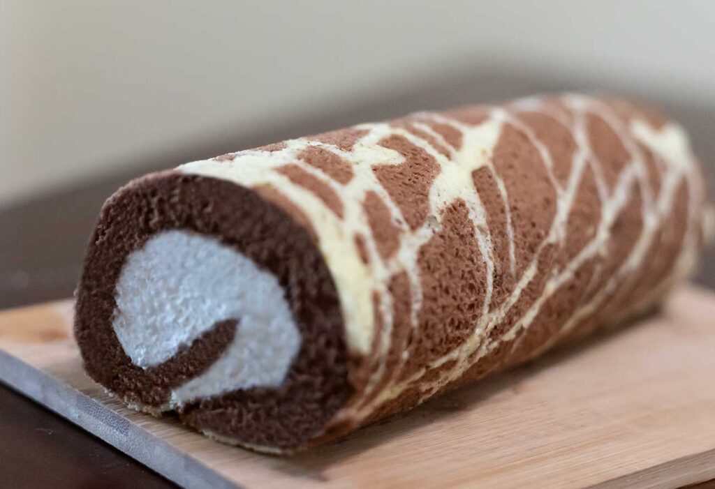 Delicious homemade roll cake with a swirl pattern, filled with creamy filling and topped with powdered sugar.